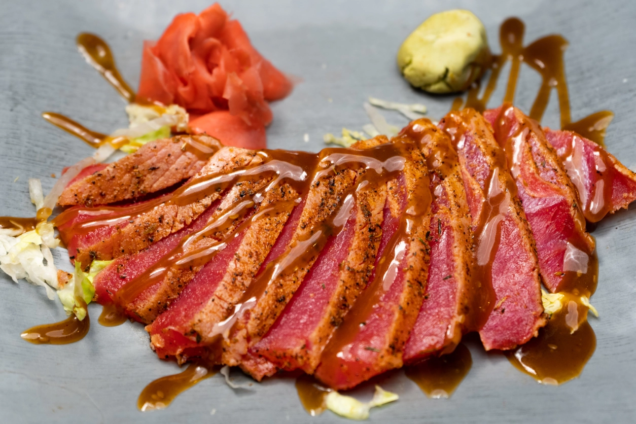 Seared tuna slices with ginger and sauce.